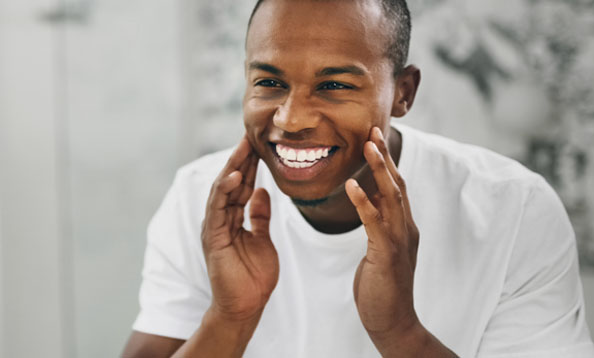 Man examining teeth in mirror